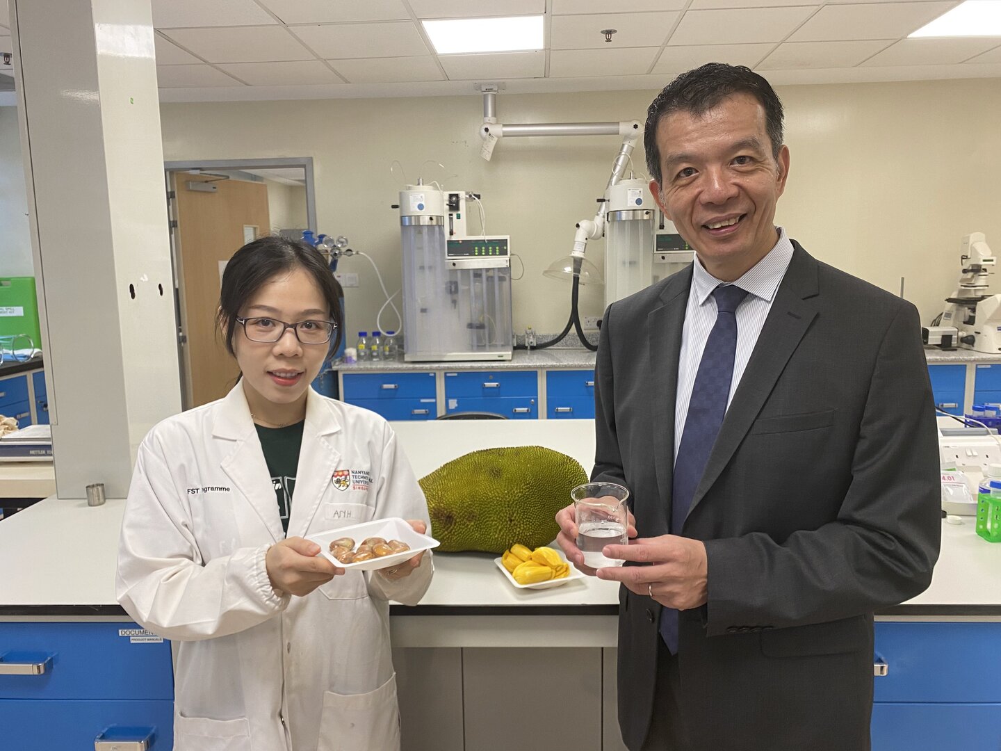 Ms Tram Anh Ngoc Le, a PhD student from the Food Science and Technology (FST) programme at NTU, and NTU Professor William Chen, Director of the Food Science and Technology, presenting jackfruit seeds and the lactic acid produced from the seeds