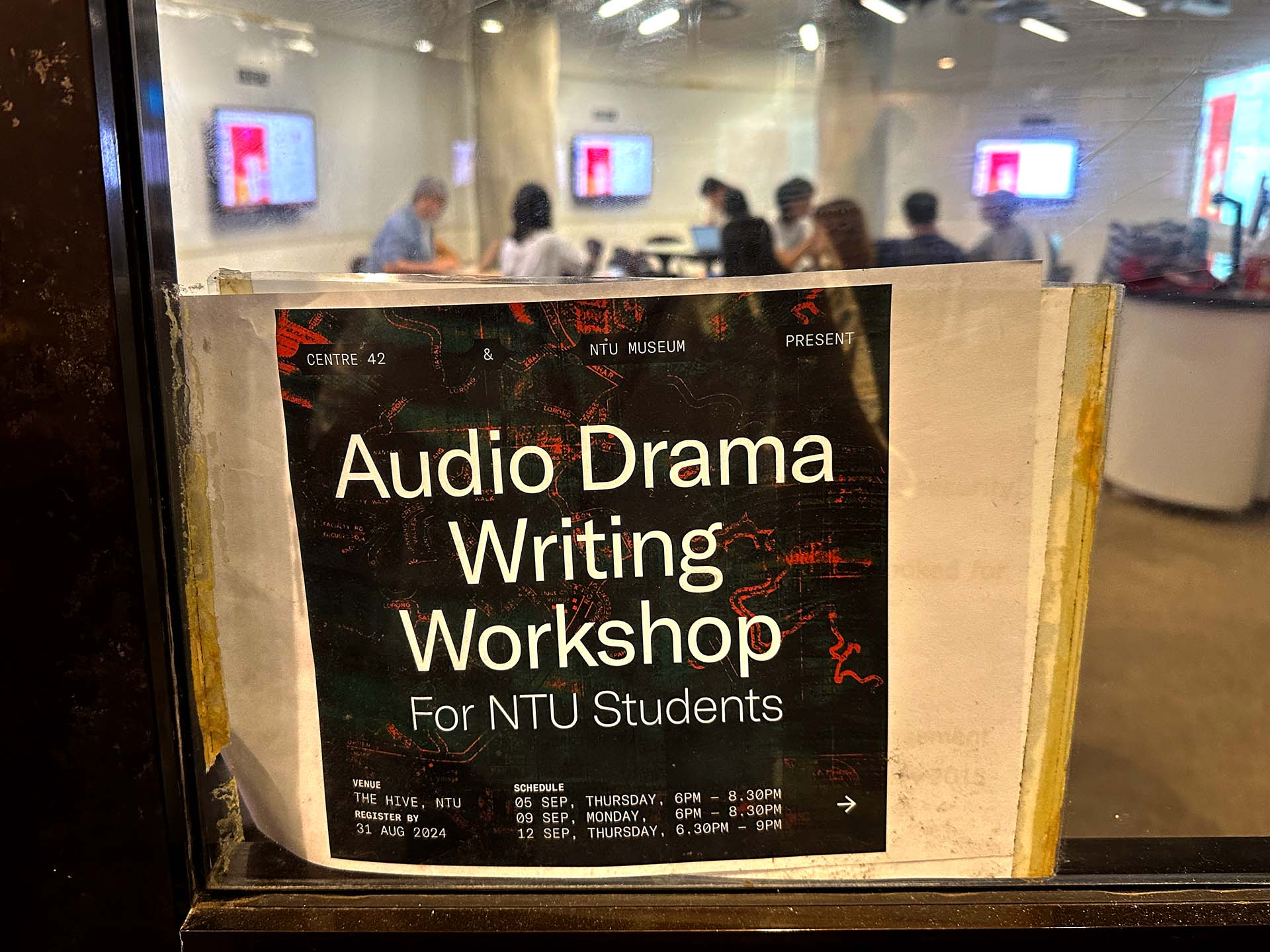 Sign in door for Audio Drama Writing Workshop with workshop in session in the background