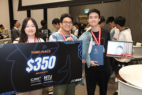 Photo of a group of three NUS High students, holding a big prize cardboard infront of a camera.