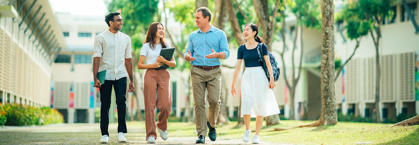 Male Caucasian Teacher Walking in Main NTU Campus Grounds with 3 Young Adult Students