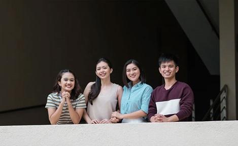 Smiling Group of 4 Students In A Stairway and Corridor Wideshot (720x432px)