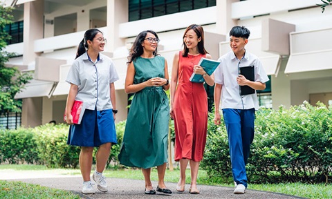 Walking Tanned Female Teacher in Green Dress and Chinese Girl in Red Dress Walking with 2 Secondary School Students Wideshot (720x432px)